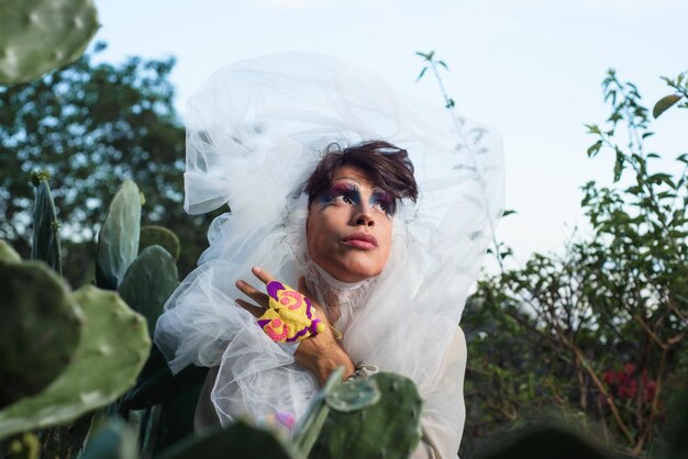 Retrato de uma drag queen em um cenário rural Pessoa de gênero não binário interagindo com a natureza