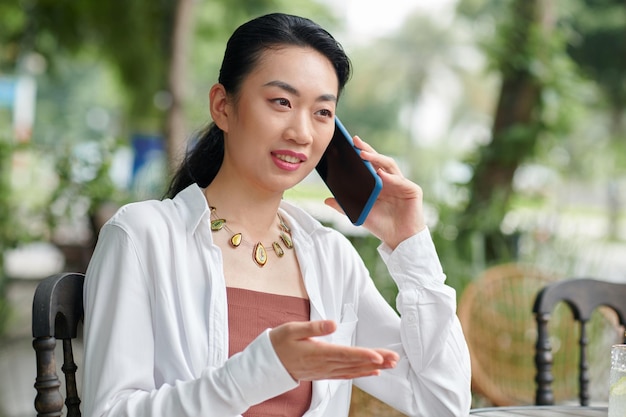 Retrato de uma empreendedora sorridente a falar ao telefone com um colega