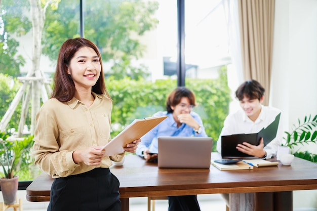 Retrato de uma empresária asiática atraente em pé durante o trabalho com a equipe de negócios de trabalho em equipe