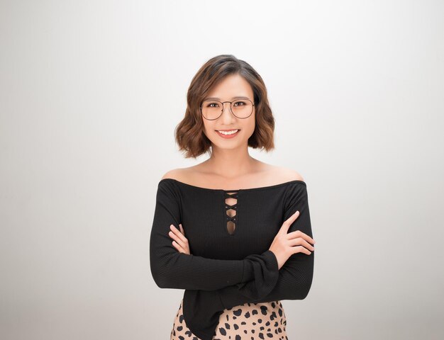 Retrato de uma empresária asiática sorridente em pé com os braços cruzados e olhando para a câmera isolada sobre fundo branco