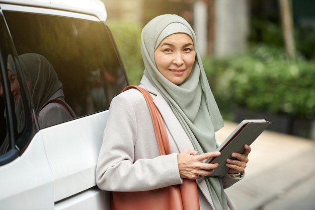 Retrato de uma empresária muçulmana sorridente em hijab segurando um tablet