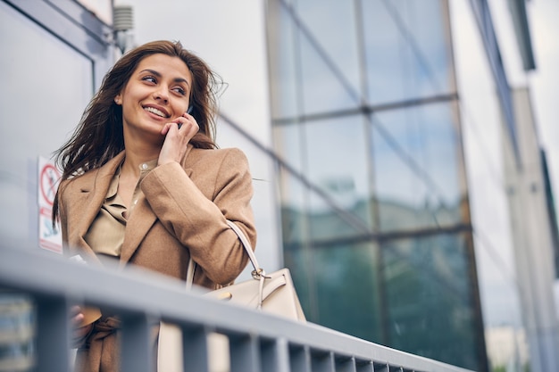 Retrato de uma empresária satisfeita com o celular na mão e olhando para longe