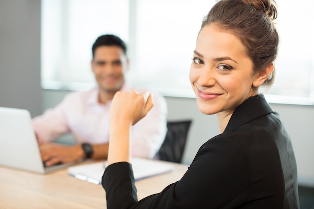 Retrato de uma empresária sorridente, sentada à mesa