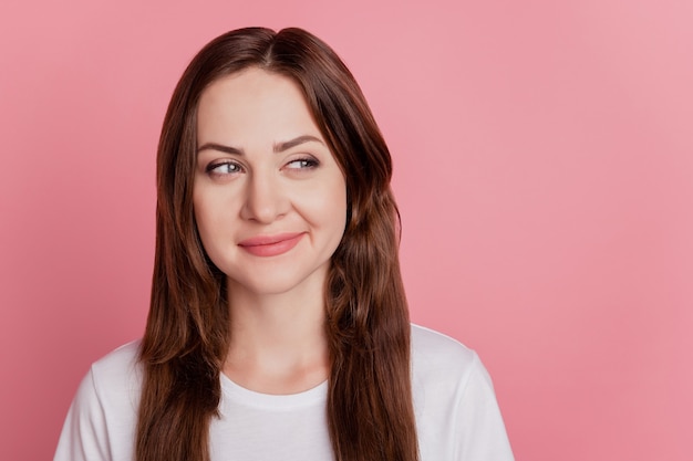 Retrato de uma encantadora menina brincalhona astuta parece um espaço vazio no fundo rosa