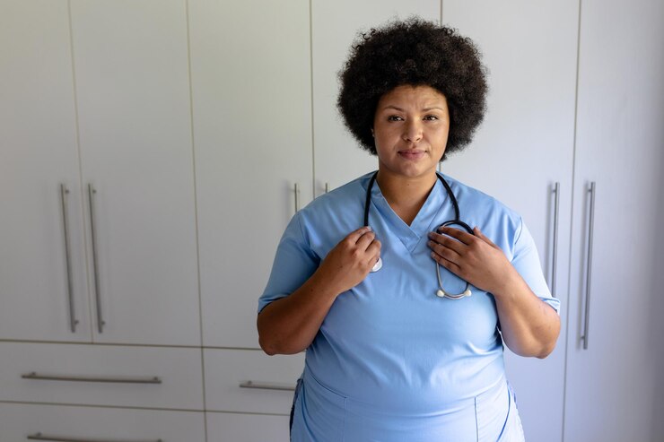 Foto retrato de uma enfermeira afro-americana adulta com estetoscópio de pé no hospital