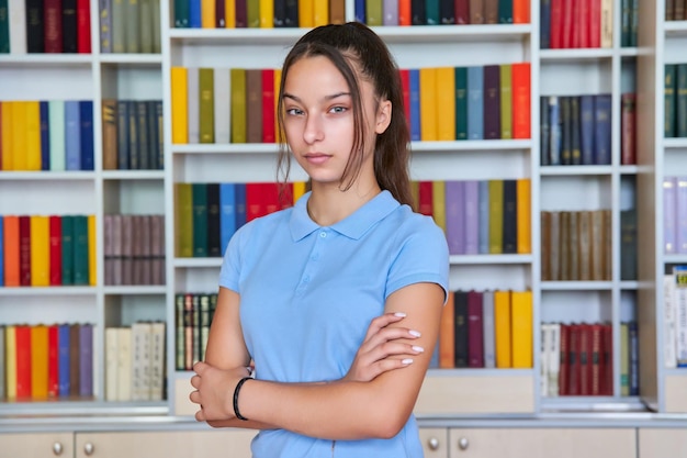 Retrato de uma estudante adolescente confiante olhando para a câmera na biblioteca