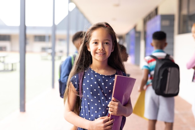 Foto retrato de uma estudante caucasiana sorridente no corredor da escola primária com espaço para cópias