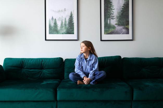 Retrato de uma estudante de camisa azul sentada no sofá em casa