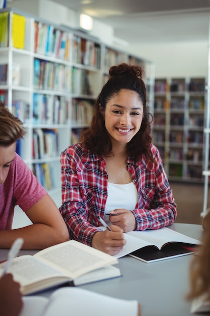 Retrato de uma estudante feliz estudando com seus colegas na biblioteca