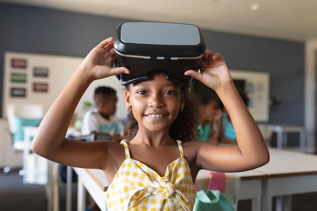 Retrato de uma estudante primária afro-americana sorridente com óculos VR na sala de aula