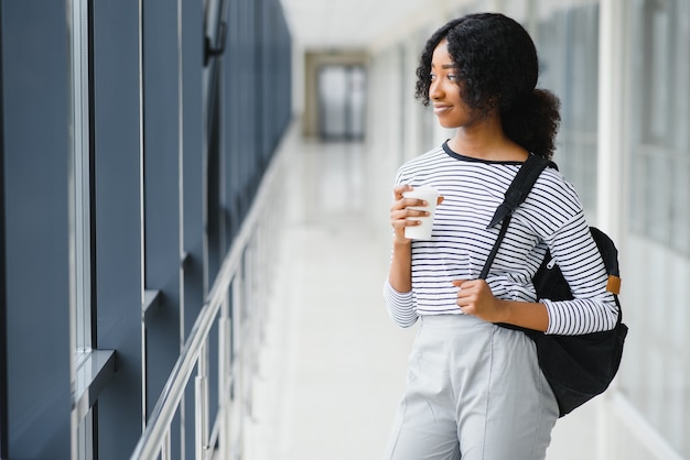 Retrato de uma estudante universitária africana com cabelo preto encaracolado em um corredor claro