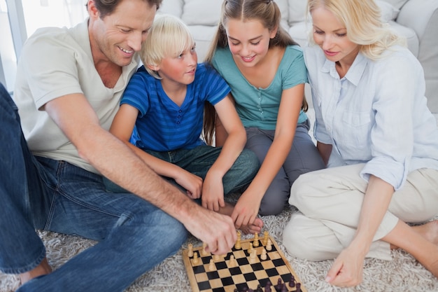 Retrato de uma família alegre jogando xadrez