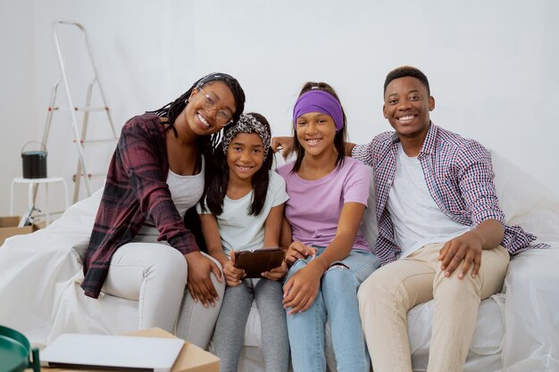 Retrato de uma família amorosa feliz e sorridente, sentada em um sofá durante uma reforma de apartamento