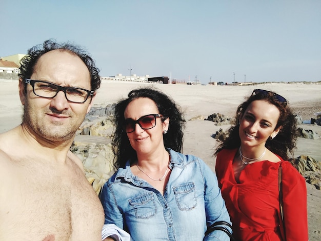 Foto retrato de uma família de pé na praia contra o céu