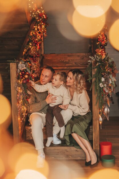 Retrato de uma família feliz em camisolas bege de tricô esperando o Papai Noel dentro de casa