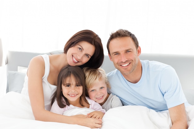 Retrato de uma família feliz sentada na cama