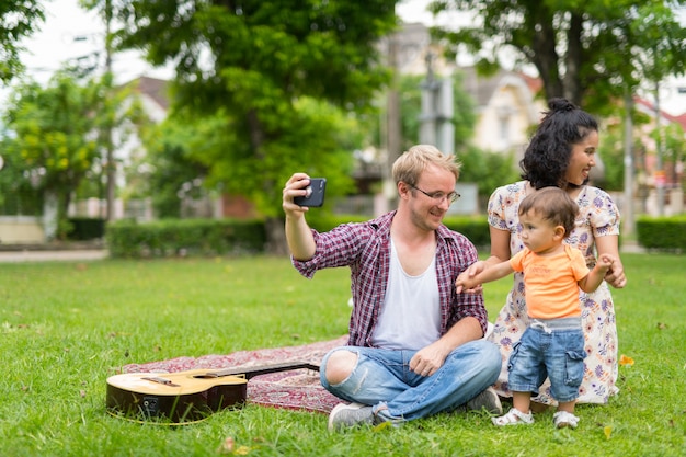 Retrato de uma família multiétnica feliz com uma criança se unindo ao ar livre