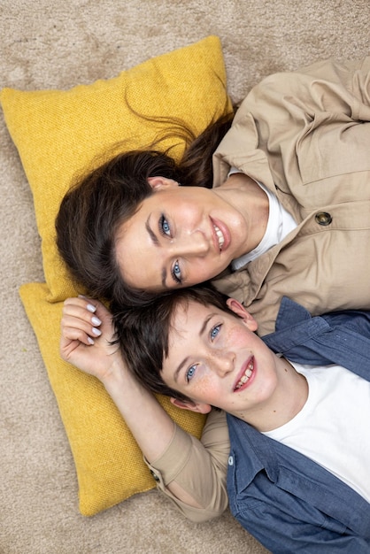 Retrato de uma família uma mãe e um filho adolescente deitado em travesseiros abraçando olhando para a câmera