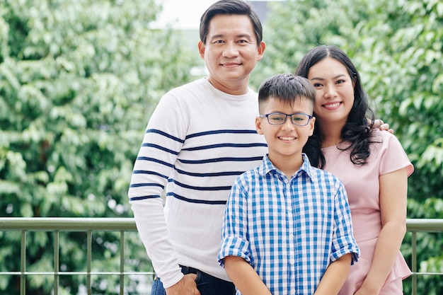 Retrato de uma família vietnamita feliz com uma criança pré-adolescente em pé ao ar livre olhando