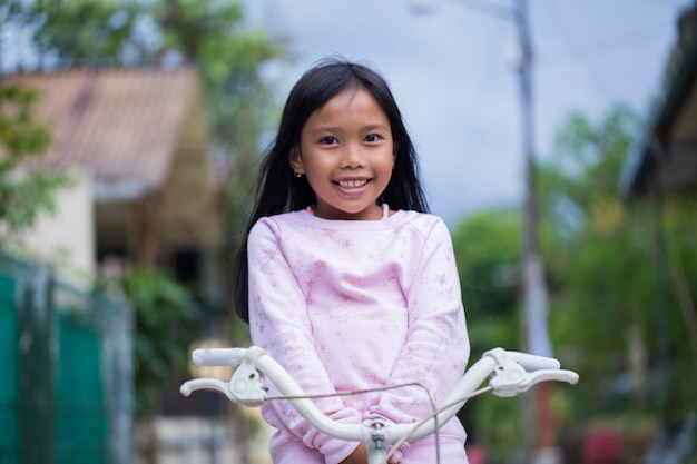 Retrato de uma feliz alegre criança asiática andando de bicicleta