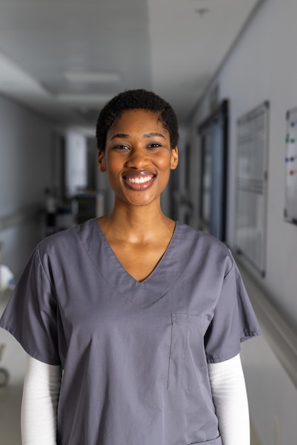 Retrato de uma feliz médica afro-americana vestindo roupas de cirurgião no corredor do hospital