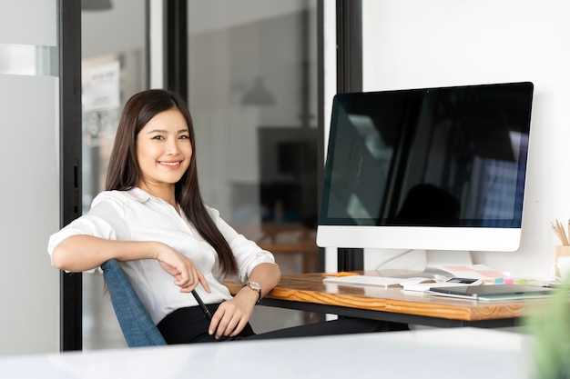 Retrato de uma feliz mulher de negócios casual sentada em seu local de trabalho no escritório