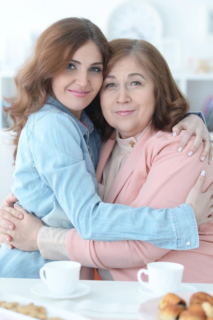 Foto retrato de uma filha adulta abraçando uma mãe idosa