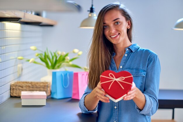 Foto retrato de uma fofa satisfeita alegre feliz sorrindo feliz mulher amada com caixa de presente em forma de coração para um dia de feriado