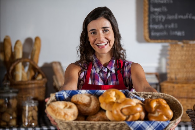 Retrato de uma funcionária segurando uma cesta de comidas doces