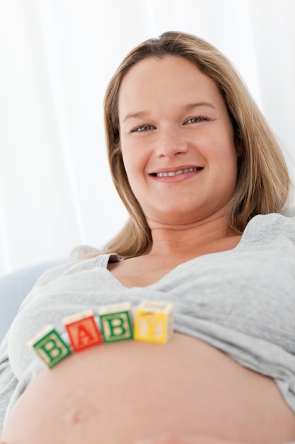 Retrato de uma futura mãe com letras de bebê em sua barriga