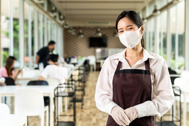 Retrato de uma garçonete asiática atraente usando um rosto com clientes em distância social