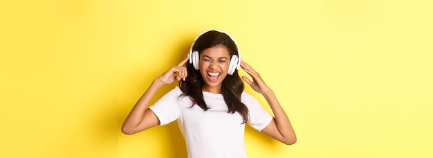 Foto retrato de uma garota africana-americana moderna gostando de ouvir música em fones de ouvido sorrindo espantada