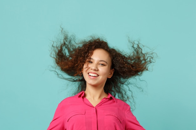 Retrato de uma garota africana sorridente em roupas casuais, em pé com fluindo cabelo, isolado no fundo da parede azul turquesa no estúdio. emoções sinceras de pessoas, conceito de estilo de vida. simule o espaço da cópia.