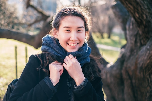 Retrato de uma garota asiática feliz Ela olha para a câmera e sorri embrulhada em um lenço