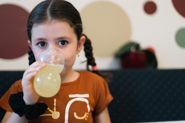 Retrato de uma garota caucasiana bebendo refrigerante de um copo