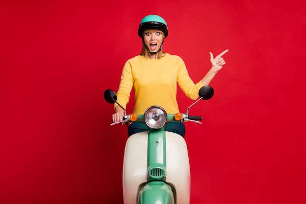 Foto retrato de uma garota espantada andando de motocicleta mostrando o espaço da cópia na parede vermelha