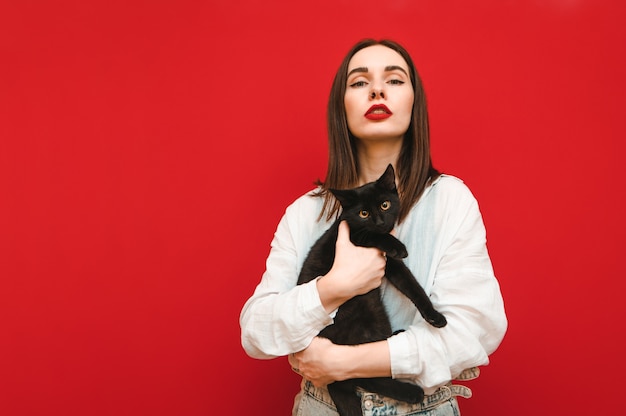 Retrato de uma garota fashion em roupas leves, posando com um gato