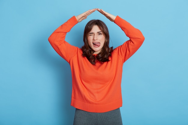 Retrato de uma garota feliz em uma camisa laranja se sentindo segura e confiante embaixo da casa