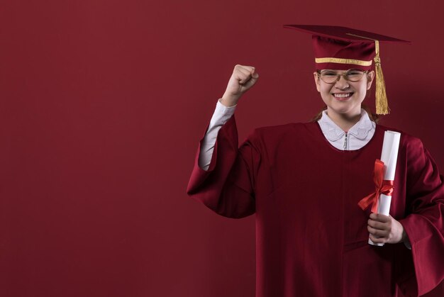 retrato de uma garota graduada em um boné de formatura em um fundo vermelho