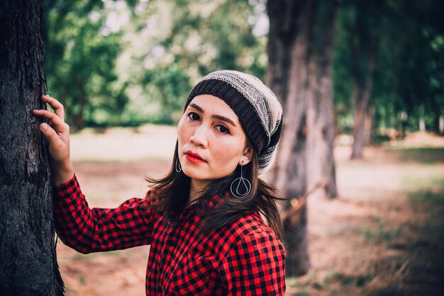 Retrato de uma garota hipster asiática no fundo da floresta ela usa chapéu estilo vintage Conceito de moda de menina alegre povo da tailândia