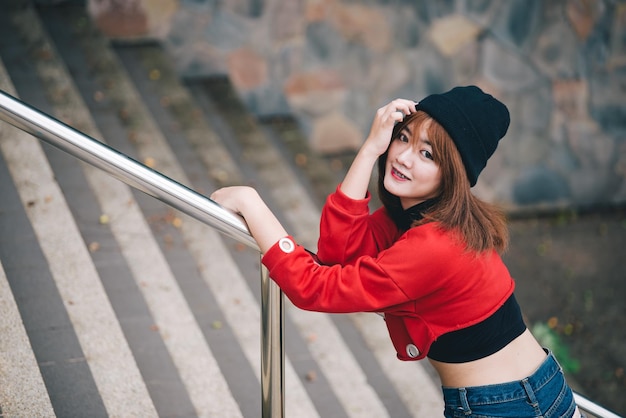 Retrato de uma garota hipster no fundo da parede de tijolos, linda mulher asiática posando para tirar uma foto, kawai