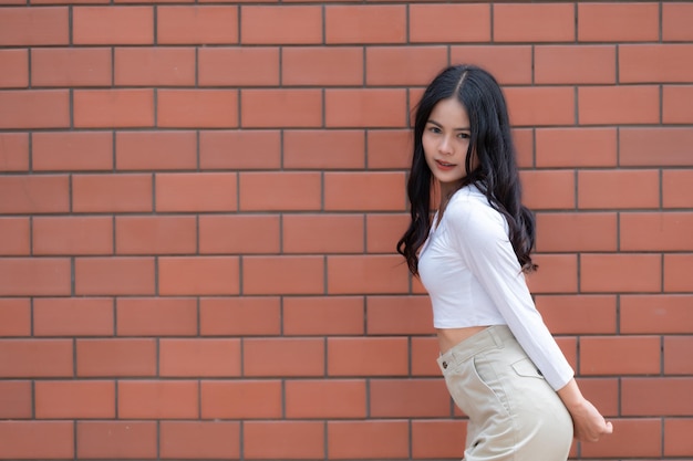 Retrato de uma garota hipster no fundo da parede de tijolos Linda mulher asiática posando para tirar uma fotoEstilo kawaii