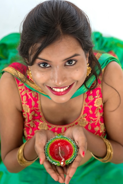 Foto retrato de uma garota indiana segurando diya e celebrando diwali ou deepavali