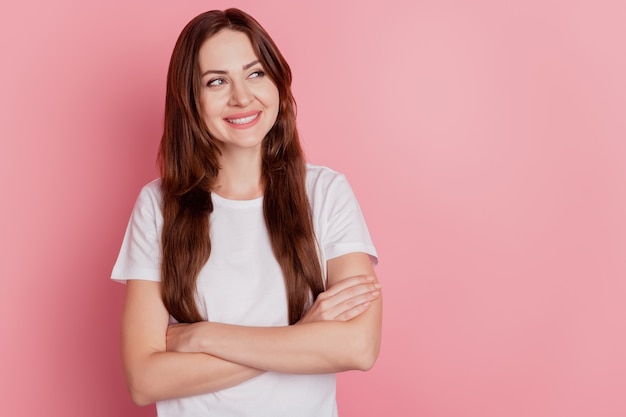 Retrato de uma garota inspirada interessada de braços cruzados olhando o espaço vazio sorriso dentuço no fundo rosa