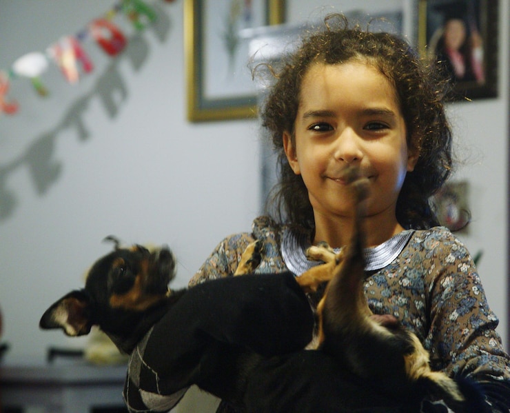 Foto retrato de uma garota sorridente com um cachorro em casa