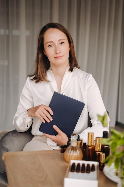 Retrato de uma garota sorridente sentada em uma poltrona Um aromaterapeuta em uma blusa branca está sentado no escritório