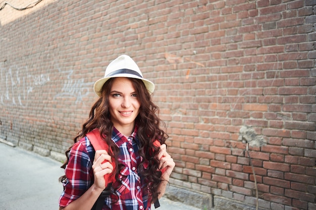 Retrato de uma garota turista com um chapéu em um fundo de um prédio de tijolos vermelhos