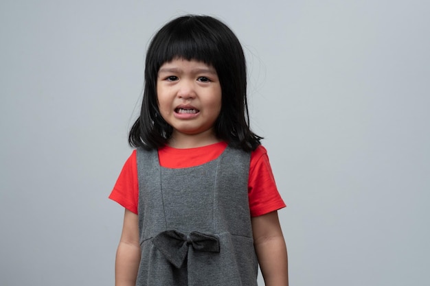 Retrato de uma garotinha asiática com raiva, triste e chorando em fundo branco isolado A emoção