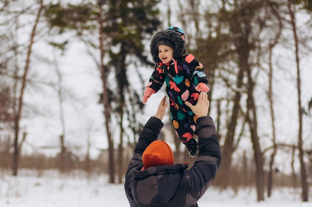 Retrato de uma garotinha feliz andando em pais na floresta de inverno se divertindo copiando o espaço