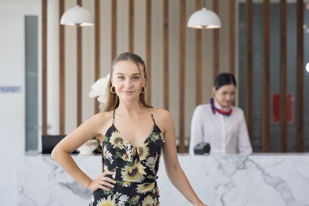 Retrato de uma hóspede com bagagem esperando para fazer o check-in no hotel, conceito de estilo de vida de viagem feliz